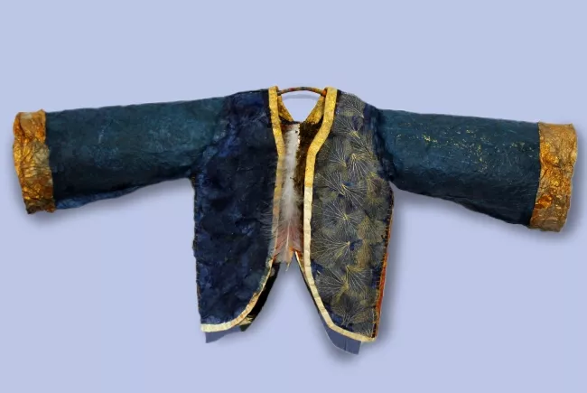 Sculpture en papier de Viviane Fontaine, intitulée ”Pèlerinage”, représentant un gilet bleu, agrémenté de dorures dorées, avec au bout de ses manches, une bande dorée