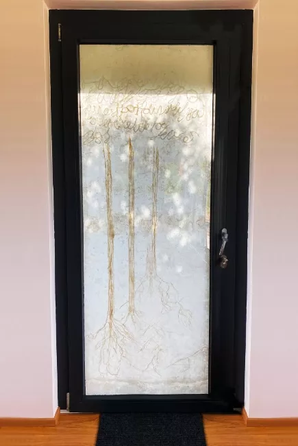 Tableau en papier de Viviane Fontaine, incorporé dans le vitrage d'une porte d'entrée et représentant des arbres se reflétant sur l'eau